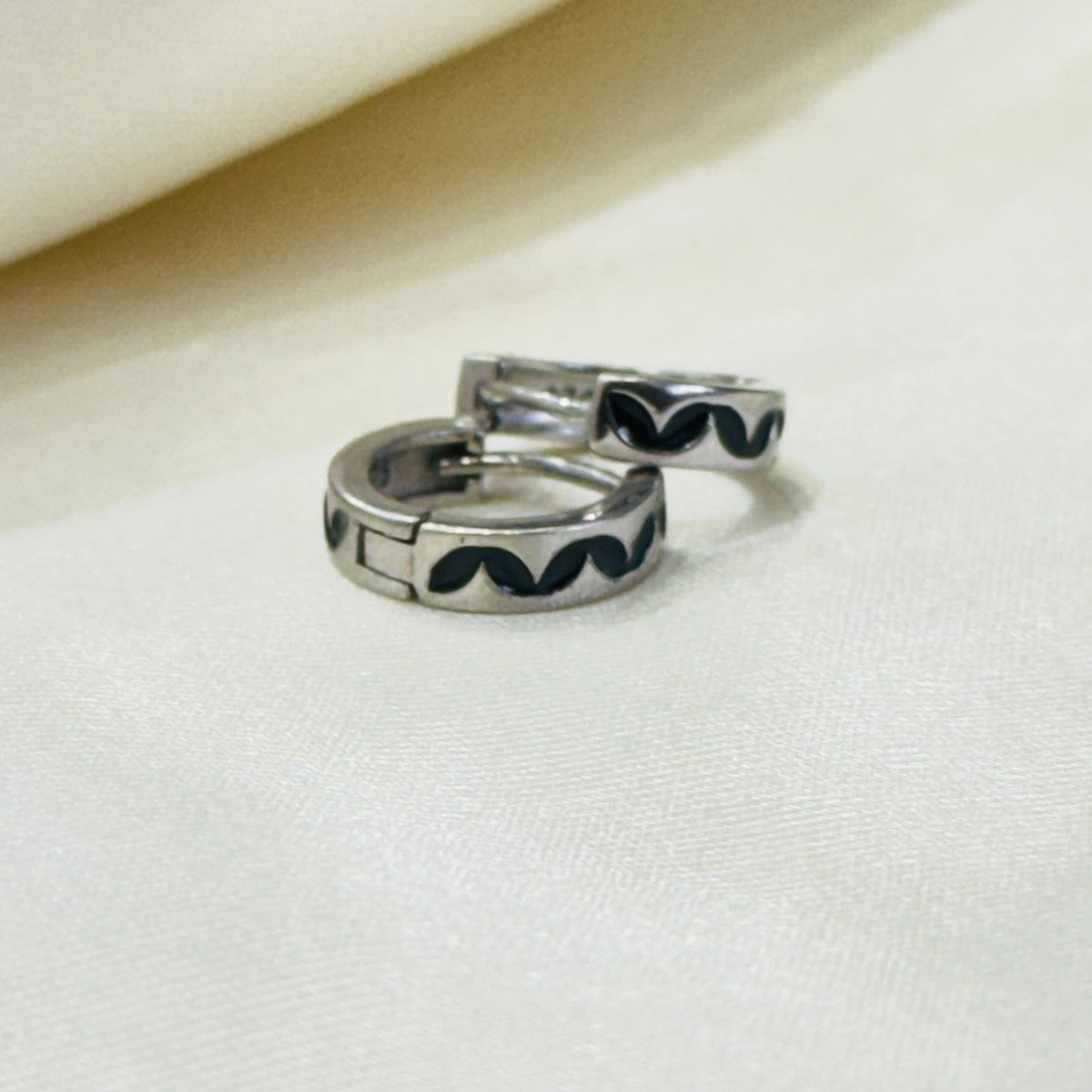Black enamel 925 sterling silver men's hoop earrings on ivory fabric