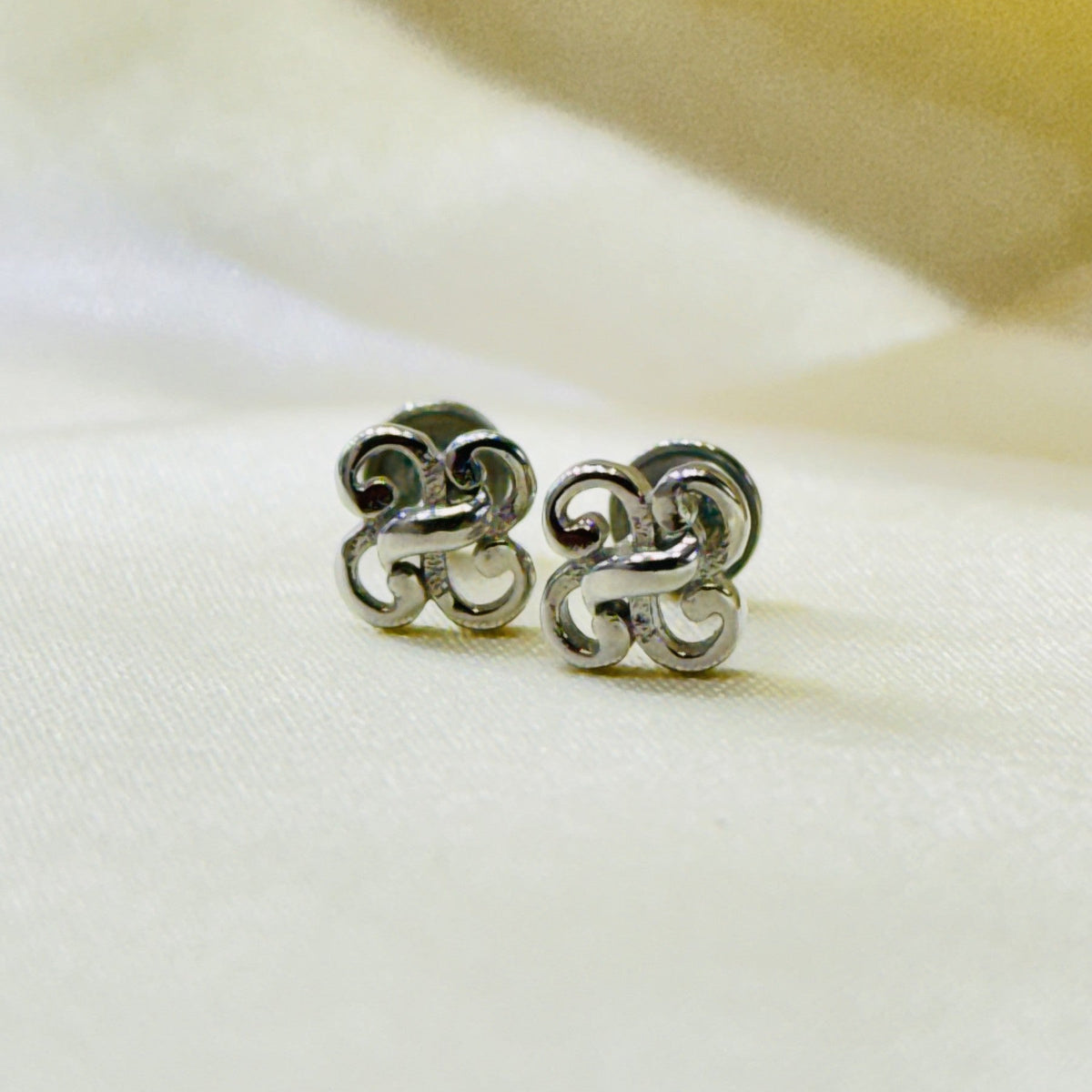 Interlocking knot design 925 sterling silver stud earrings on ivory fabric